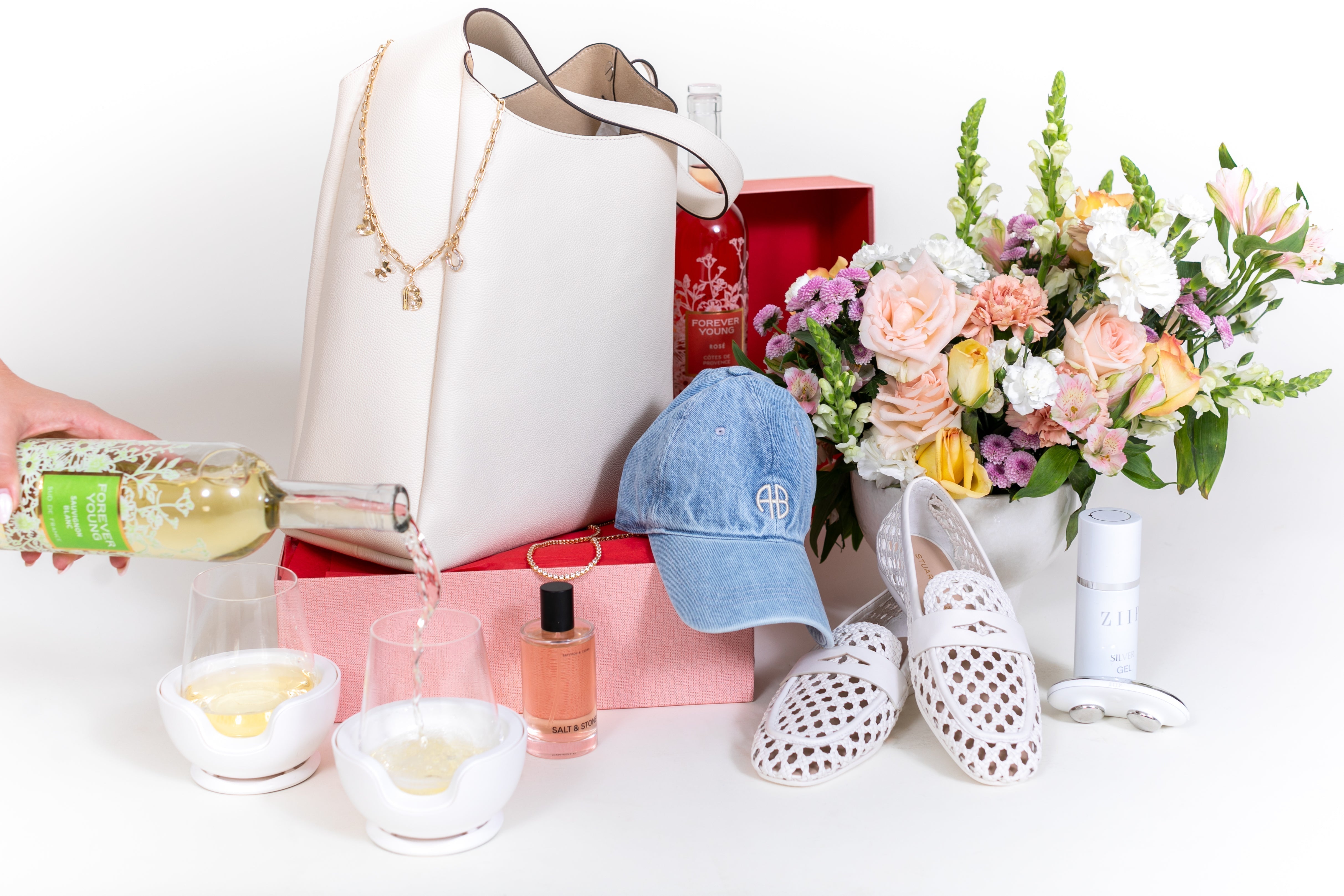 flowers, a leather bag, a baseball hat, shoes, wine, and various other gifts for mother's day against a white background